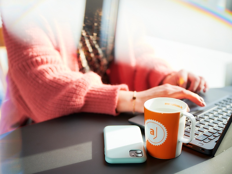 women at computer with a mug from adesso