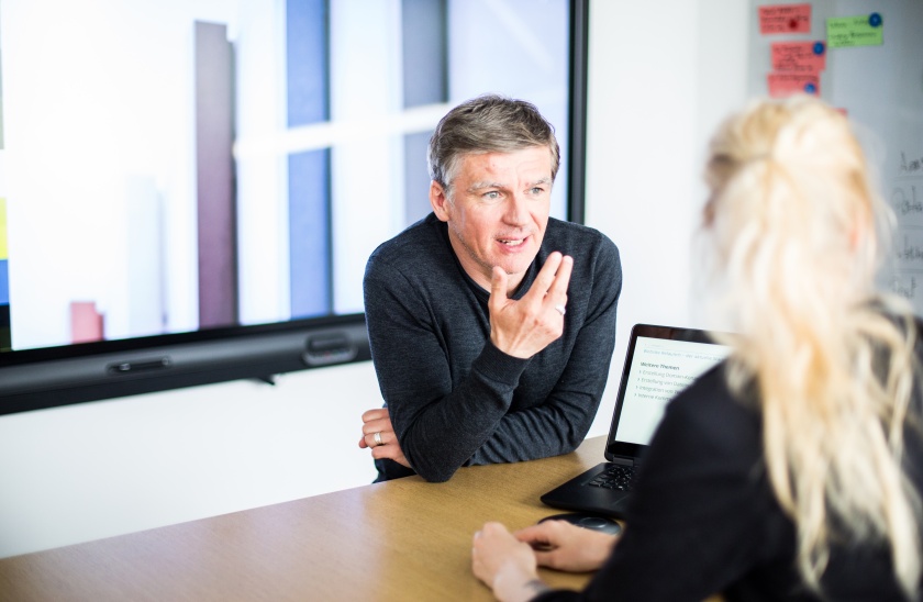 A male adessi explaining something in a meeting