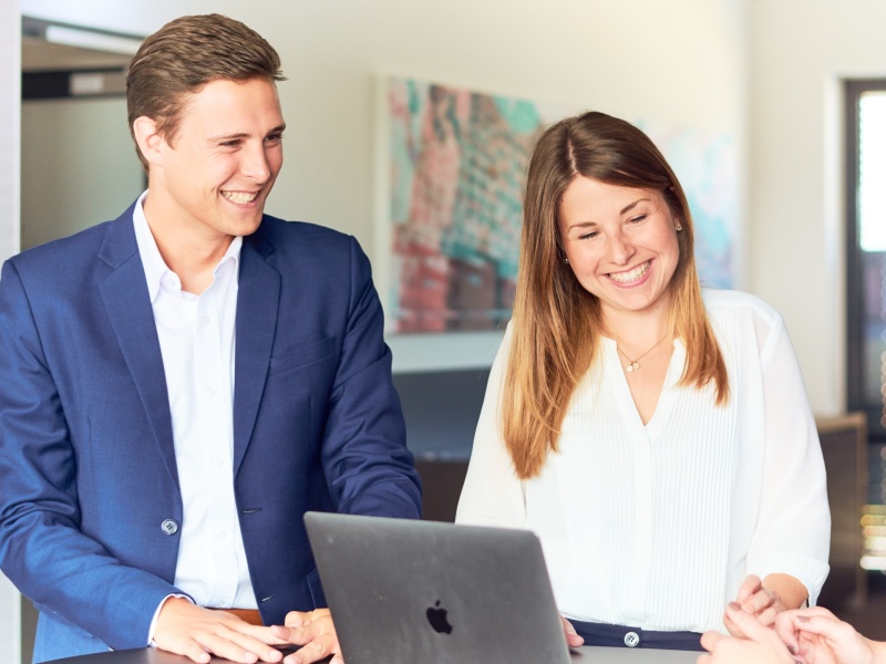 Male and female adessi in a meeting smiling.